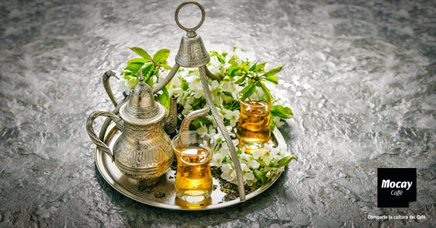 Bandeja con dos vasos de té moruno o té a la menta y tetera tradicional marroquí en color plateado. Hojas de menta alrededor de las tazas de té.